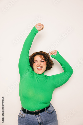 Joyful curvy woman celebrating with arms raised in green top