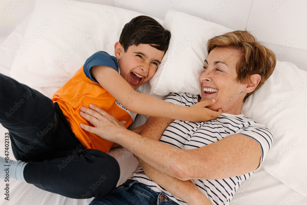 Joyful grandmother and grandson playing on a bed Joyful grandmother and grandson playing on a bed
