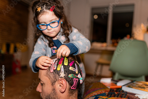 Playful Daughter Decorating Dad's Hair at Home