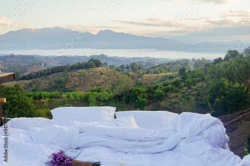 White pillow and blanket with mountain scenery view in morning. Outdoor on balcony terrace. Travel on holiday vacation.