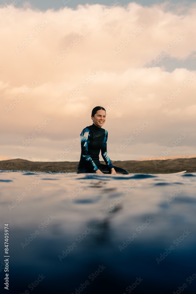 Portrait of a professional surfer floating happily on her surfboard