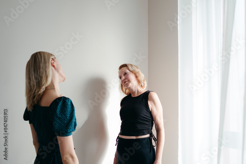 Two women do exercises standing by the window photo