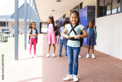Biracial students standing outside school building, wearing backpacks and smiling © WavebreakMediaMicro
