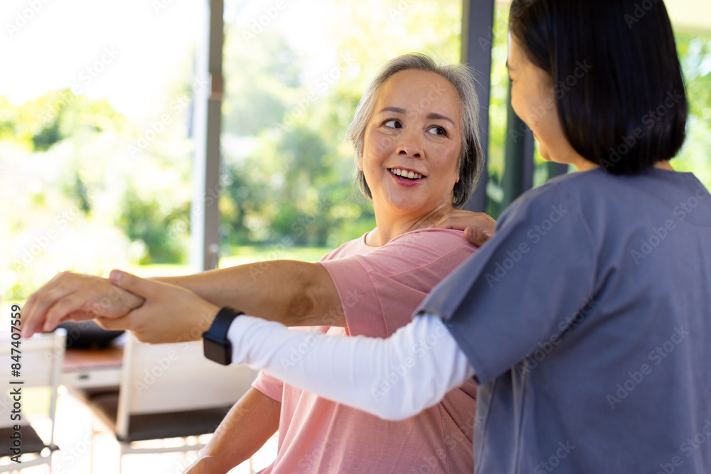 Asian senior woman receiving physical therapy at home from caregiver
