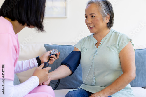 Asian senior woman having blood pressure checked by Asian nurse healthcare worker