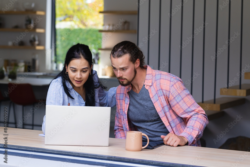 Young diverse couple are looking at a laptop together Young diverse couple are looking at a laptop together