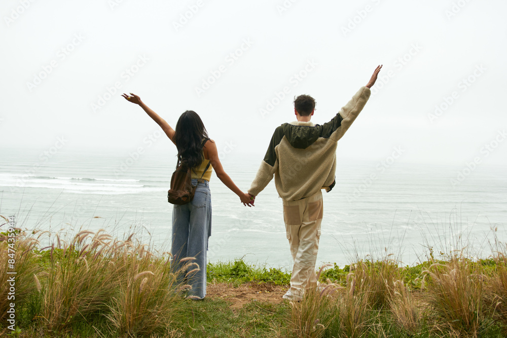 Pareja de novios sujetados de la mano mirando el paisaje frente al mar Pareja de novios sujetados de la mano mirando el paisaje frente al mar