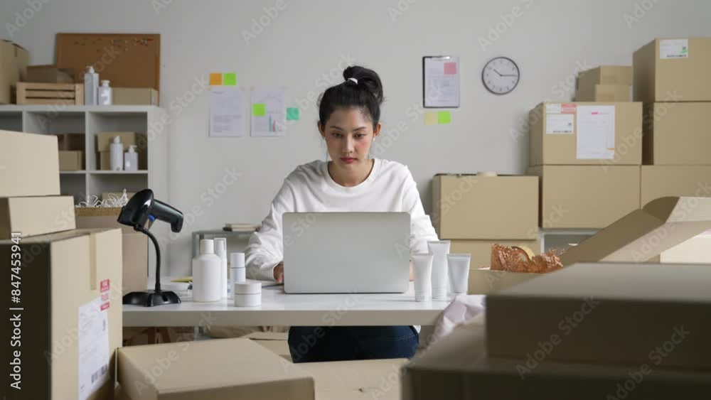 Asian woman online seller confirming orders from customer on the computer laptop. E-commerce business owner working at store warehouse. Asian woman online seller confirming orders from customer on the computer laptop. E-commerce business owner working at store warehouse.