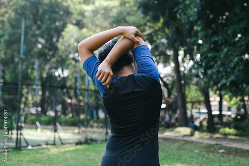 Fitness, Bodybuilder Man Stretching At Park, Exercise And Workout For Strong Powerful Muscles. Back view Of Elbow Warm Up.
