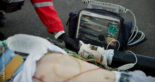 Accident, paramedic and chest with defibrillator for help, emergency and healthcare on road. First responder, medic and male victim with support, injury and life saving on tarmac with protection