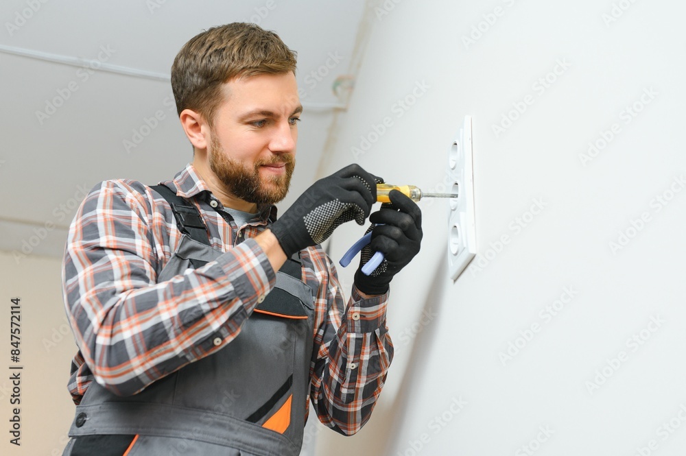 Electrician installs decorative frame on electric and TV sockets