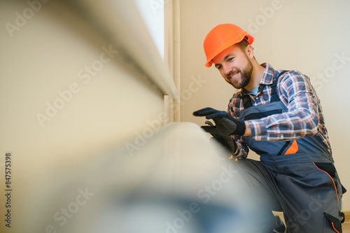 heating system installation and maintenance service. plumber installing radiator