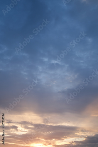 Fototapeta Naklejka Na Ścianę i Meble -  Soft blue sky combines with light of sunset to create a peaceful sky. Beautiful landscape with clouds and orange sun. Vertical image.
