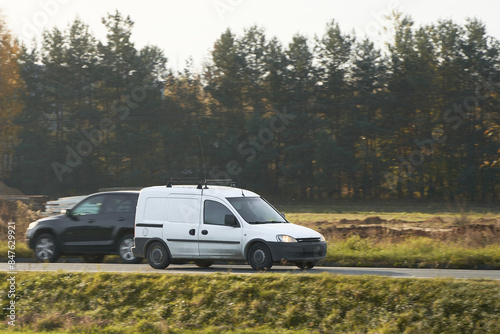 White van speeds along a scenic country road