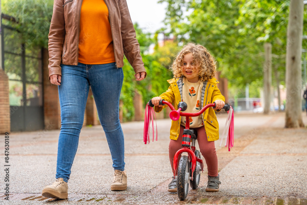 Mother helping a girl learning how to ride a bike Mother helping a girl learning how to ride a bike