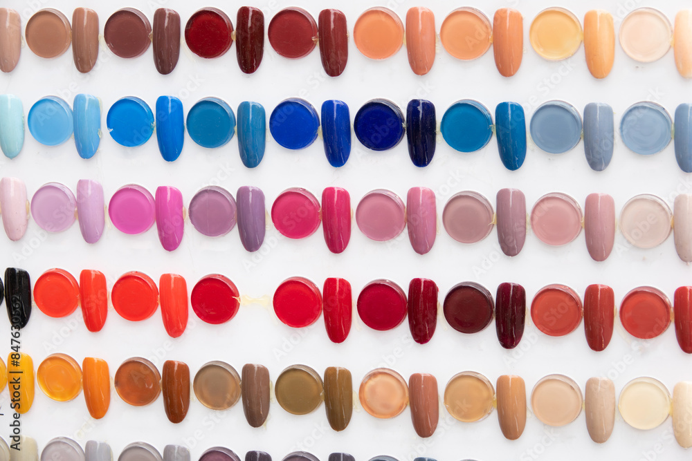 A row of nail polish bottles with a variety of colors. Concept of abundance and variety, as there are many different shades to choose from. The colors range from bright and bold to more subtle A row of nail polish bottles with a variety of colors. Concept of abundance and variety, as there are many different shades to choose from. The colors range from bright and bold to more subtle