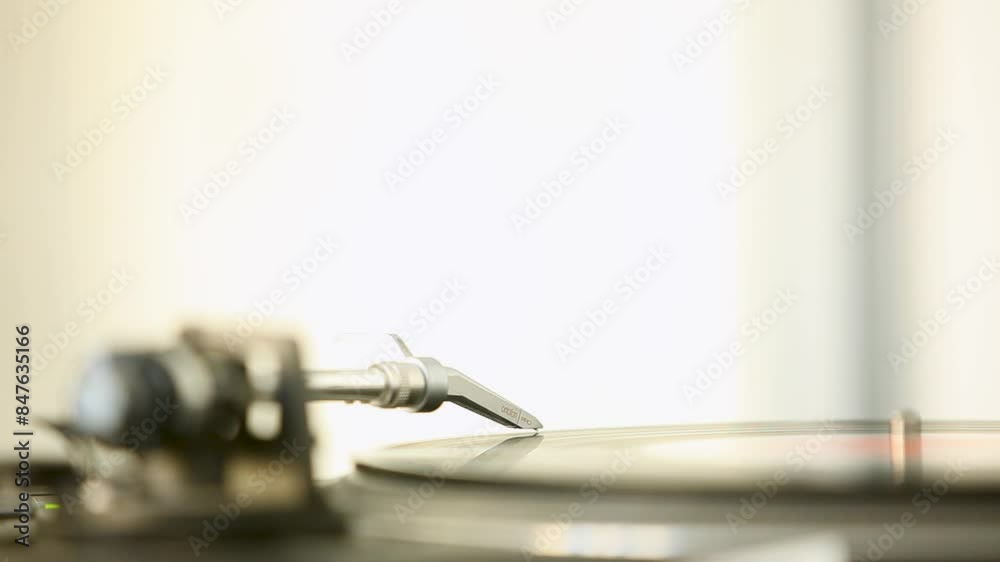 Close-up of a hand placing the needle on a vinyl record in a bright room Close-up of a hand placing the needle on a vinyl record in a bright room