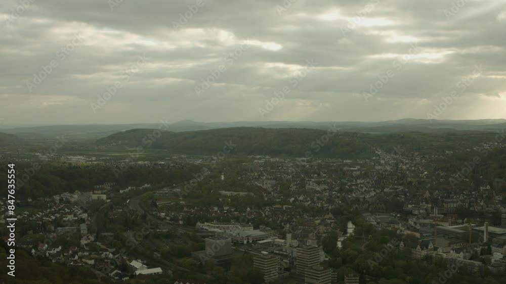 Overcast sky casts soft light over a sprawling European city nestled in lush hills, hinting at tranquility Overcast sky casts soft light over a sprawling European city nestled in lush hills, hinting at tranquility