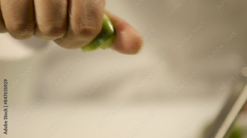 Close-up of a hand squeezing lime juice, focus on the dripping lime, soft background Close-up of a hand squeezing lime juice, focus on the dripping lime, soft background