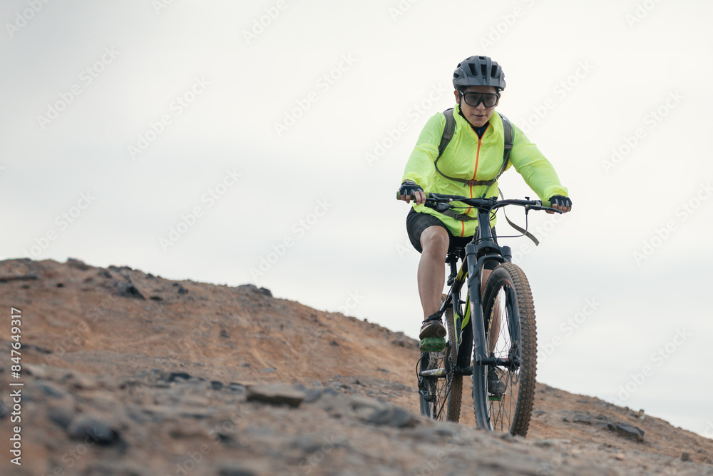 Female mountain biker descending on trail on arid landscape