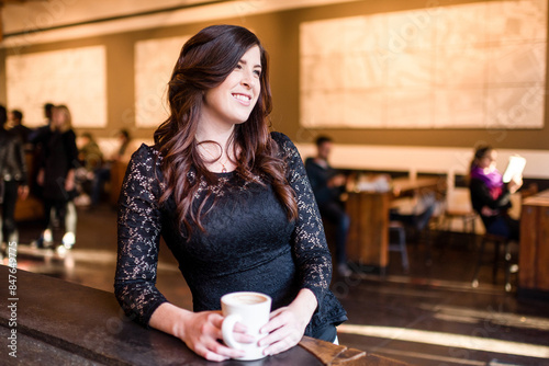 Women holding coffee mug in shop looking out window photo