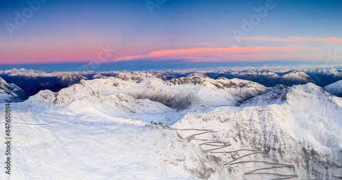 Aerial view of winding snowy mountain road at Stelvio Pass at sunrise