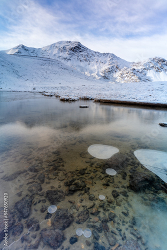 Snowy mountains reflected in a frozen lake, Braulio Valley, Valtellina photo