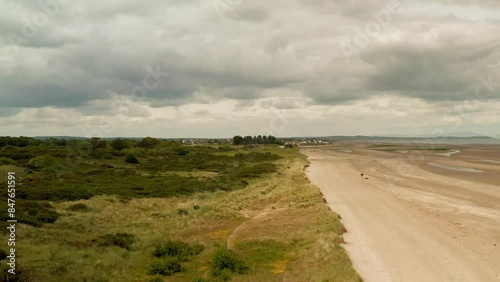 Captivating aerial footage of Laytown Beach, Ireland, shot with a drone on a cloudy summer day in 2024. The video showcases the serene coastline and grassy dunes as the drone ascends. photo