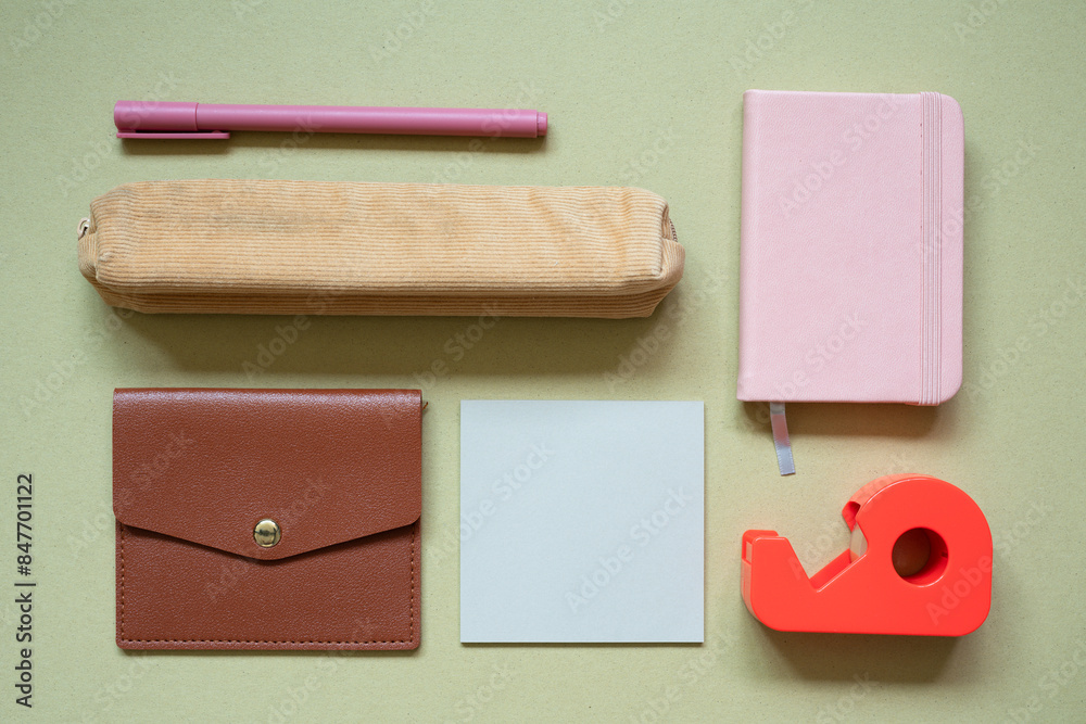 Various office and school supply. pen, pencil case, card wallet, memo pad, notebook, tape dispenser on khaki desk background. top view