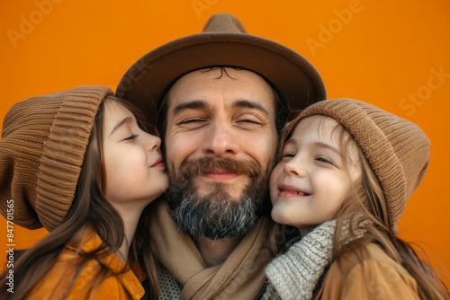 Parents with their child wearing basic t-shirts kissing father greeting daddy isolated on yellow background. Childhood concept of family and parenthood. © Mark