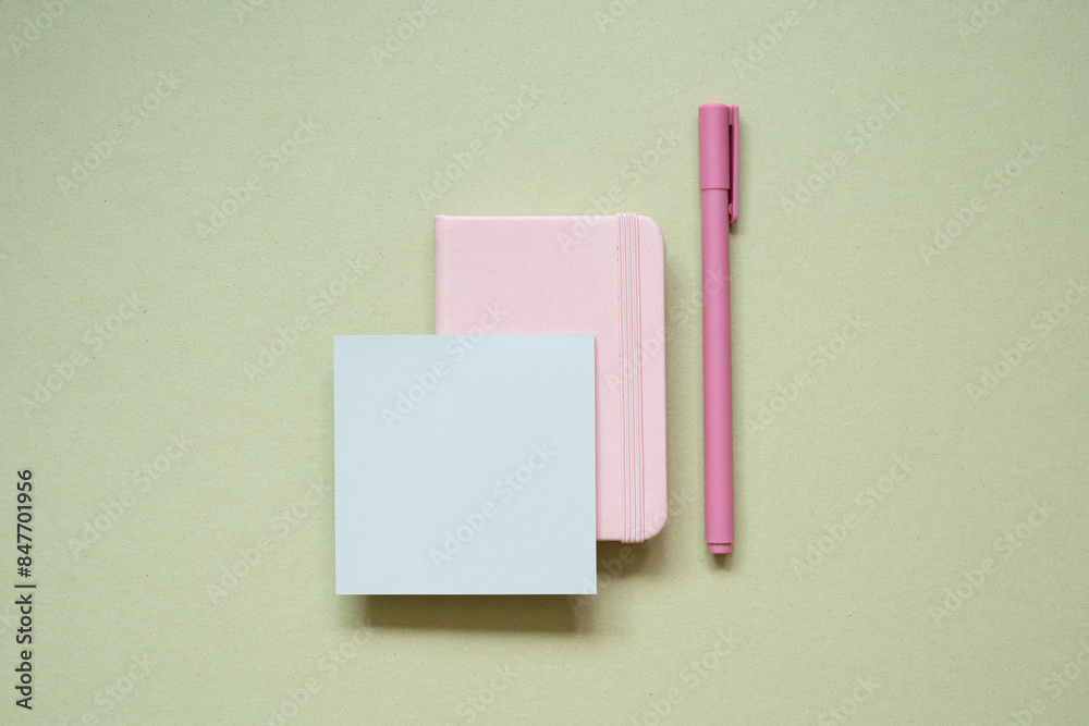 Pink diary notebook, memo pad, pen on khaki desk background. top view