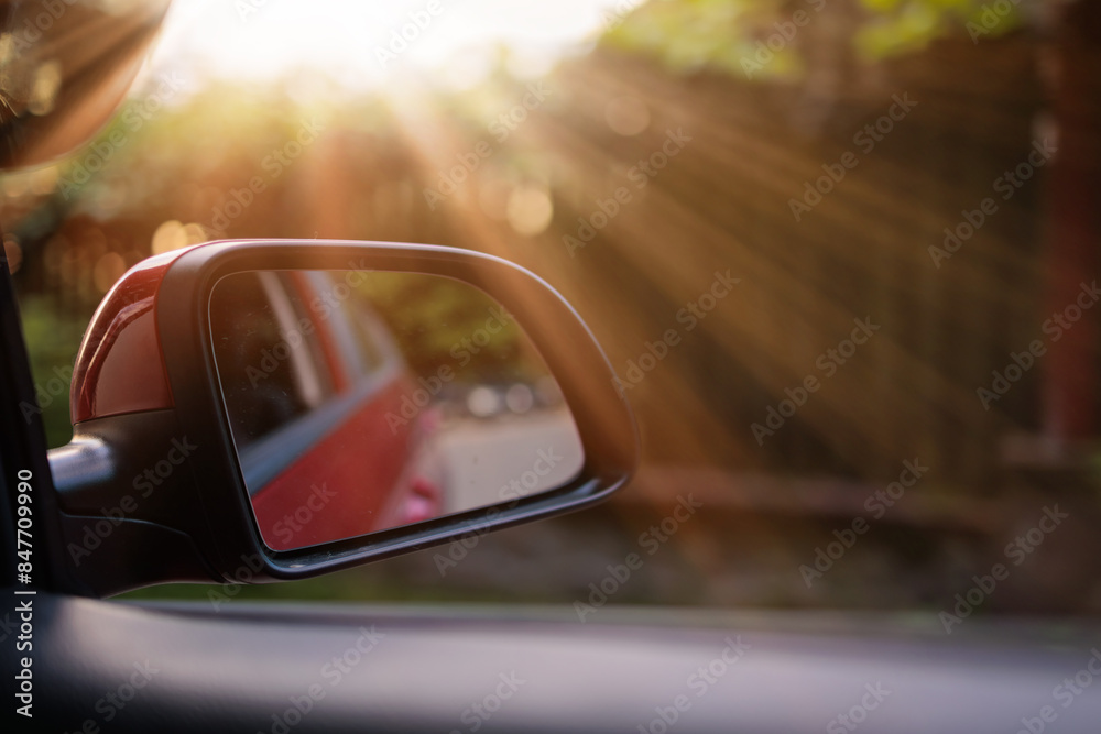 The sun is reflected in the mirror and window, evening road. View in the side rear view mirror of a car The sun is reflected in the mirror and window, evening road. View in the side rear view mirror of a car