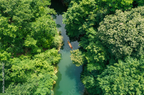 Aerial perspective of a canoe in a forest-surrounded lake backwater