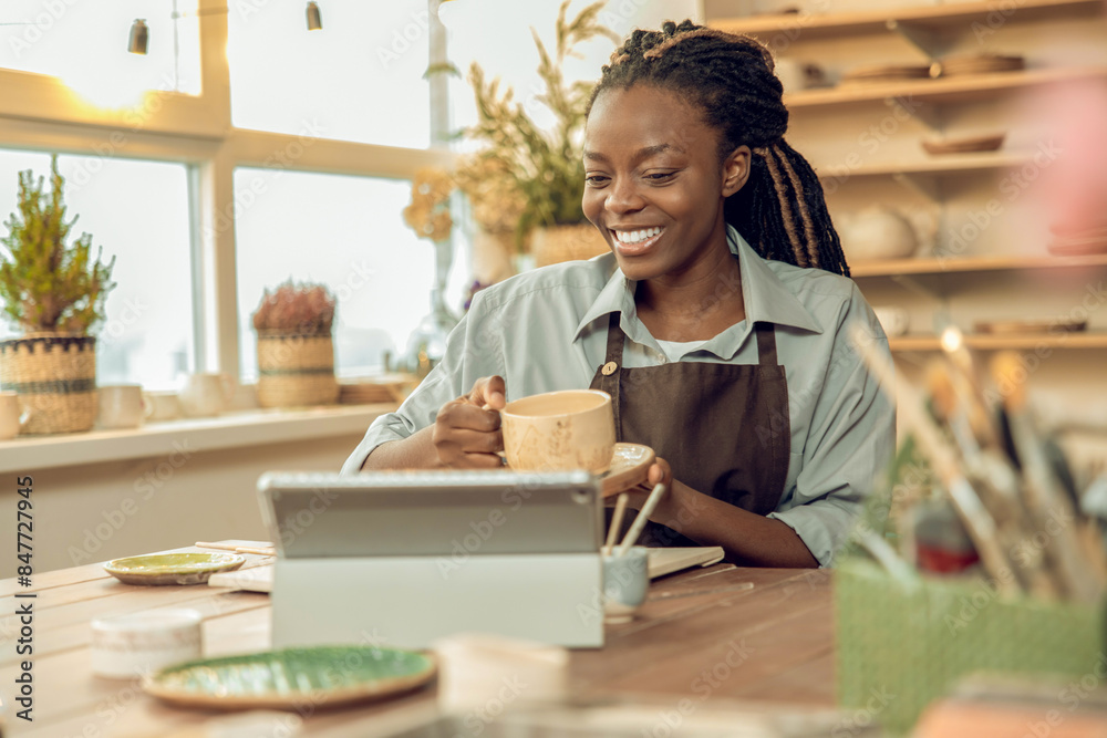 Cute smiling young woman holding a ceramic mug in hands Cute smiling young woman holding a ceramic mug in hands