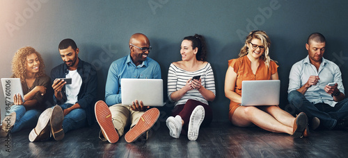 Technology, people and collaboration sitting on floor for teamwork, communication and diversity in office. Group, men and woman online for social media post, internet browsing or company research