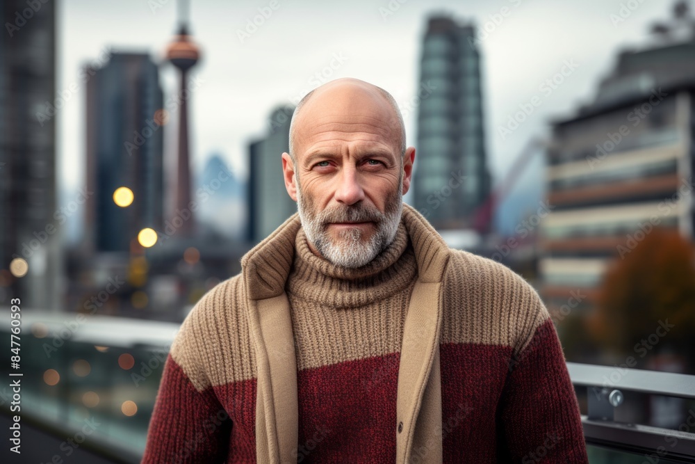 Portrait of a glad man in his 50s dressed in a warm wool sweater while standing against modern cityscape background Portrait of a glad man in his 50s dressed in a warm wool sweater while standing against modern cityscape background