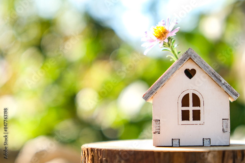 A wooden toy house in the woods, with a blurry background, stands on a wooden table. The concept of selling, buying, renting real estate.