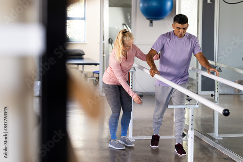 A biracial man undergoing rehabilitation exercises with female physical therapist photo
