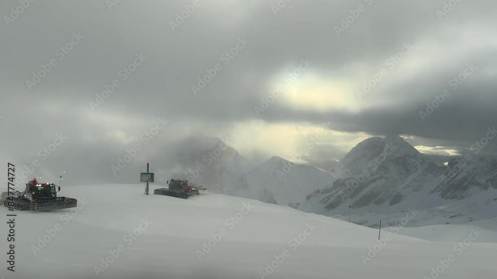 Snowplows clearing fresh snow on Zugspitze with mountains in the background, cloudy day Snowplows clearing fresh snow on Zugspitze with mountains in the background, cloudy day