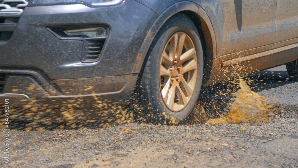 CLOSE UP Driving car hits a pothole in asphalt road and splashes muddy rainwater