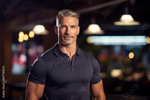 Portrait of a tender man in his 40s donning a classy polo shirt isolated in dynamic fitness gym background