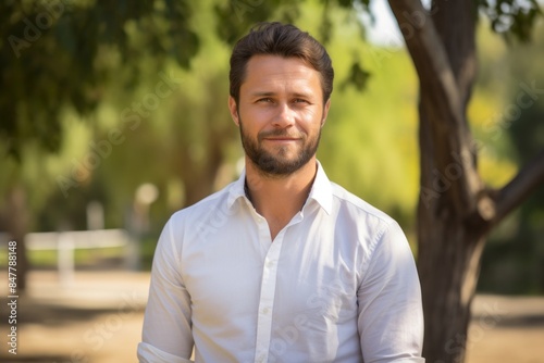Portrait of a glad man in his 30s wearing a simple cotton shirt in bright and cheerful park background