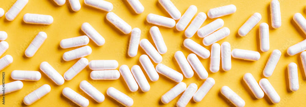 White medical capsules on yellow background. White medical capsules on yellow background.