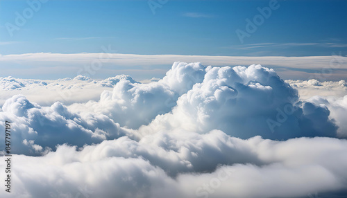 Aerial view of dense, fluffy cumulus clouds with a clear blue sky above, majestic beauty of nature from an airplane.