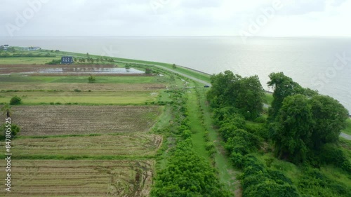 Aerial: Sea dyke view along the road, camera tilt ocean reveal, North Atlantic Ocean and Nickerie Suriname photo