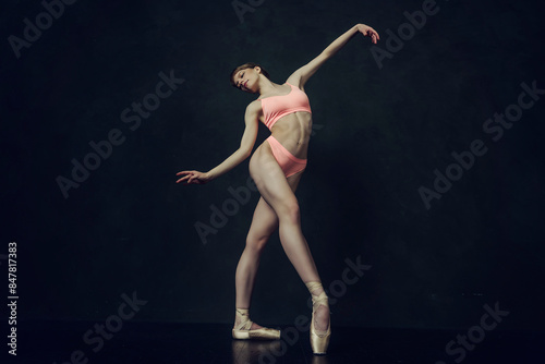 young ballerina in lingerie with a muscular body makes ballet steps demonstrating stretching and eversion