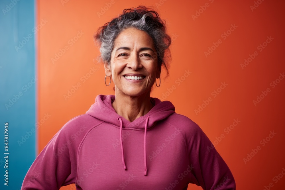 Portrait of a blissful indian woman in her 60s wearing a thermal fleece pullover isolated on vibrant yoga studio background Portrait of a blissful indian woman in her 60s wearing a thermal fleece pullover isolated on vibrant yoga studio background