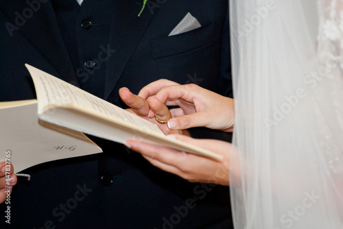 Schilderij op canvas Newlywed couple holding hands and reciting their vows from a book during a relig