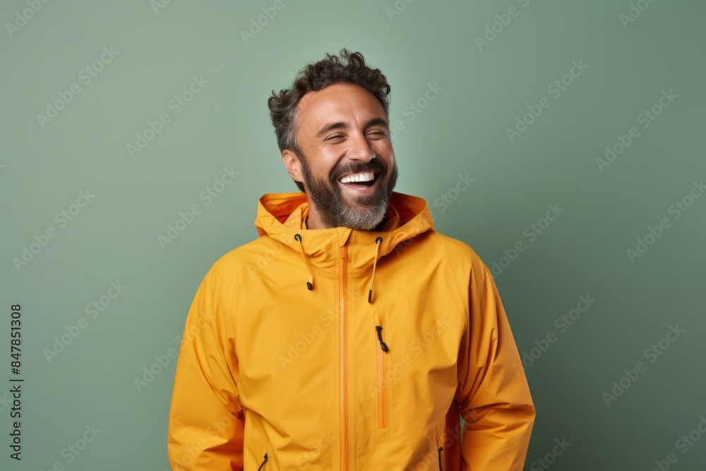 Portrait of a cheerful man in his 30s wearing a functional windbreaker while standing against minimalist or empty room background