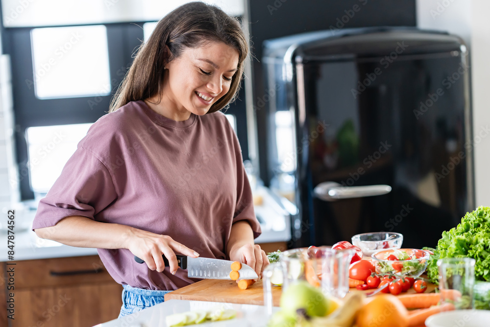 A young pretty cheerful woman is preparing a healthy various vegetable-based meal at home A young pretty cheerful woman is preparing a healthy various vegetable-based meal at home